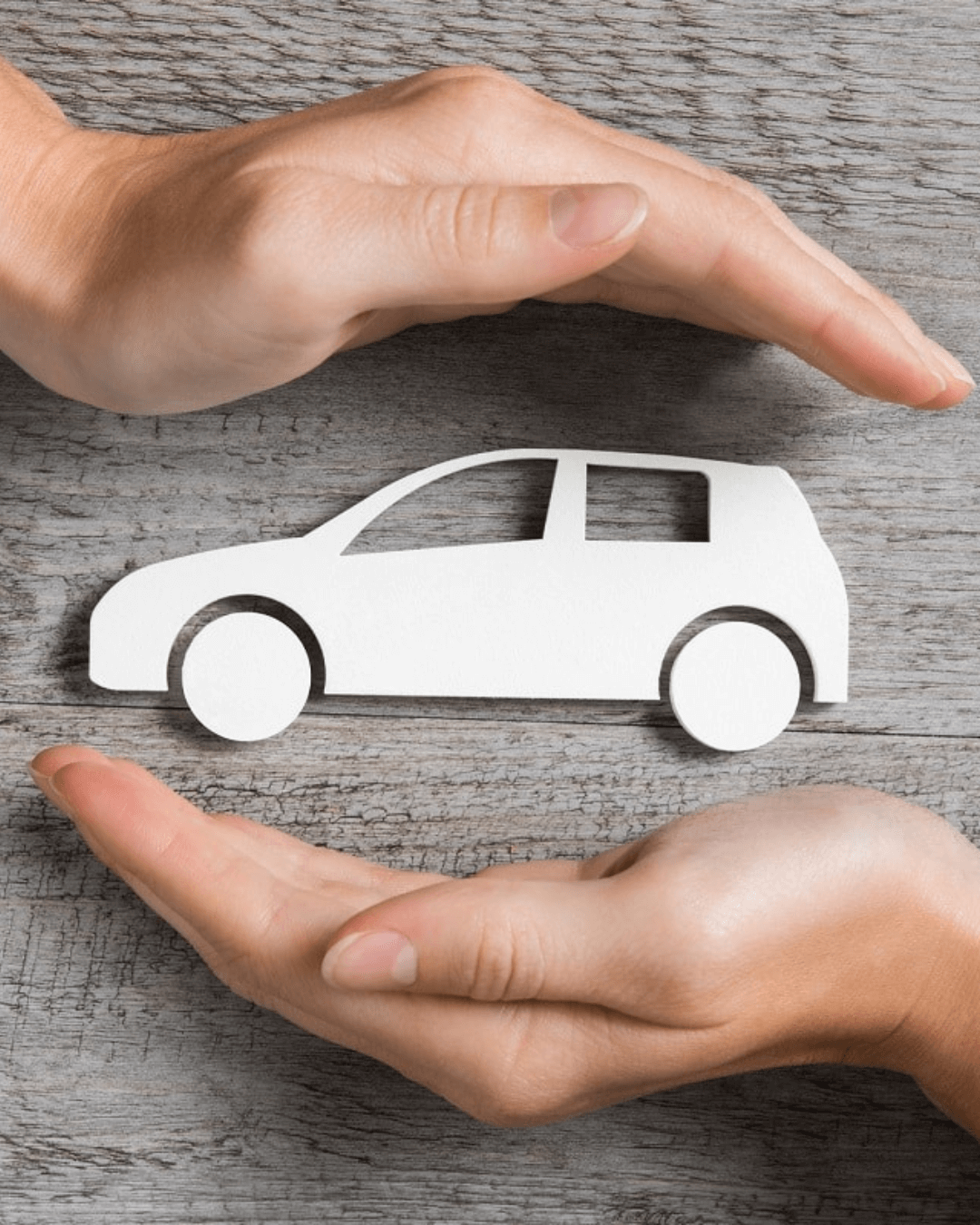 Deux mains entourant une voiture miniature en papier, symbolisant la protection et la sécurité d'une assurance auto