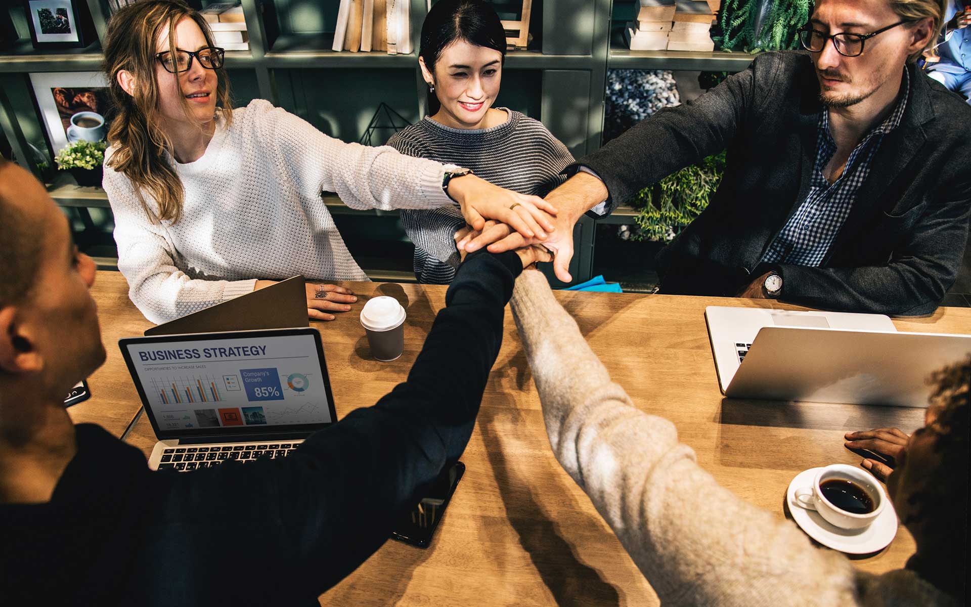 Équipe de professionnels en réunion se félicitant pour leur collaboration autour d'une table de travail.