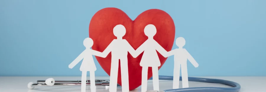 une famille (quatre silhouettes) devant un cœur rouge, entourée d'un stéthoscope. Cette image symbolise la protection de la santé à travers une mutuelle ou une complémentaire santé