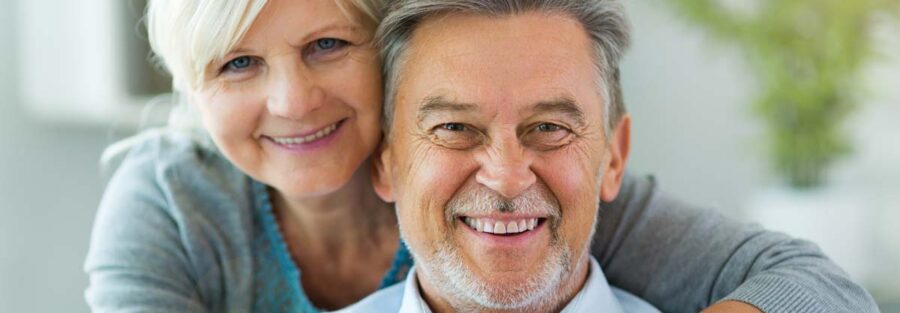 Un couple de seniors souriants, représentant le bien-être et la sécurité que peut offrir une mutuelle santé adaptée à leurs besoins