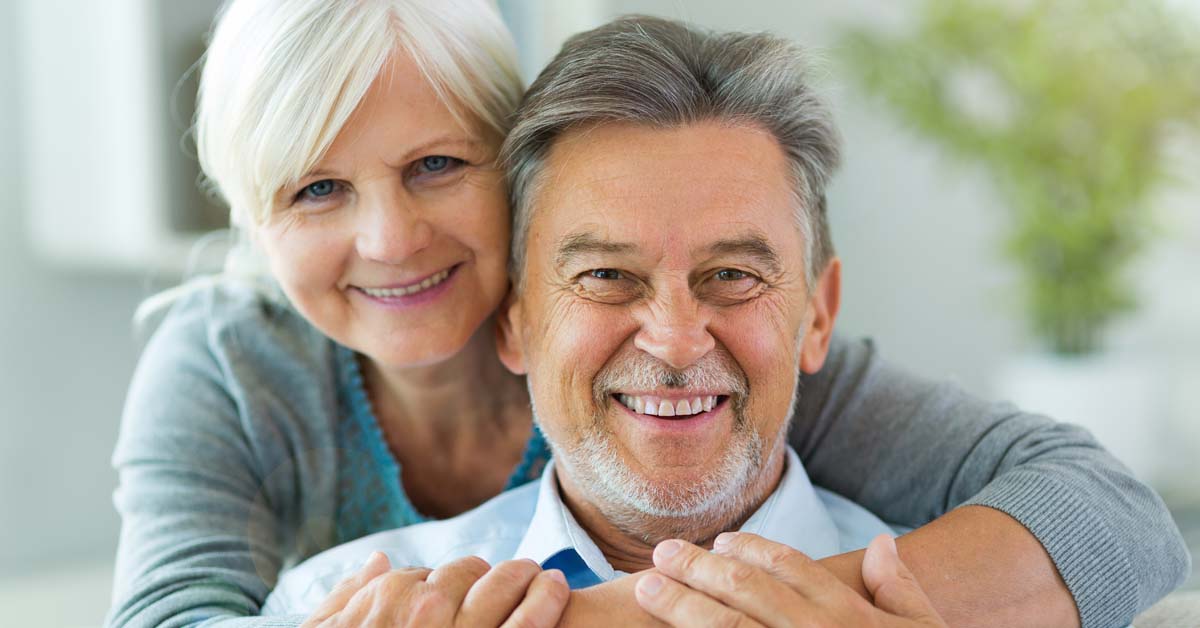 Un couple de seniors souriants, représentant le bien-être et la sécurité que peut offrir une mutuelle santé adaptée à leurs besoins